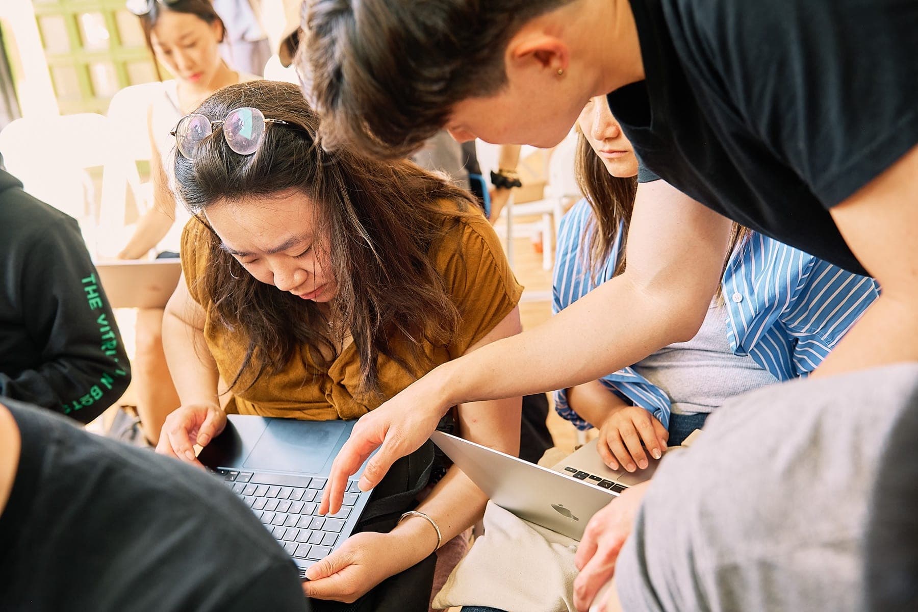 Hands-on AI workshop attendee helping another builder on a laptop